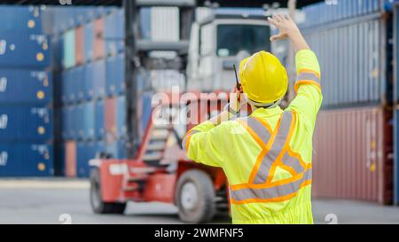 A dock foreman with a radio standing in front of cargo containers Stock Photo