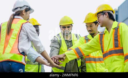 The dock workers stand with their hands together in the container terminal. Logistic, teamwork Stock Photo