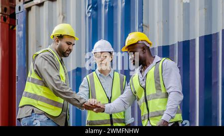 The dock workers stand with their hands together in the container terminal. Logistic, teamwork Stock Photo