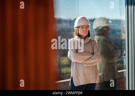Female architect wearing white hardhat posing on construction site, selective focus Stock Photo