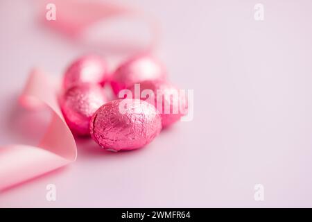 Easter chocolate eggs wrapped in aluminium foil on the pink background. Stock Photo