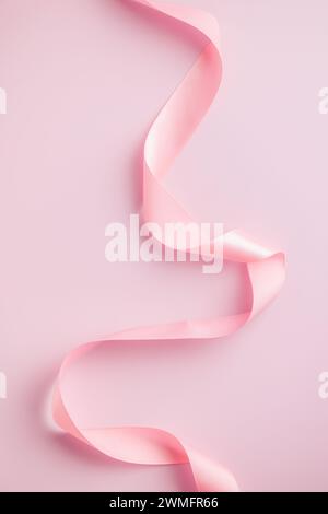Curled pink ribbon on the pink background. Stock Photo