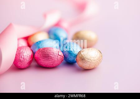 Easter chocolate eggs wrapped in aluminium foil on the pink background. Stock Photo