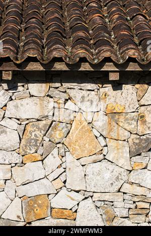 A Rustic stone wall and roof with ceramic tiles Stock Photo