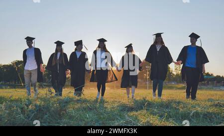 Graduate students walking through an evening meadow at sunset. Stock Photo
