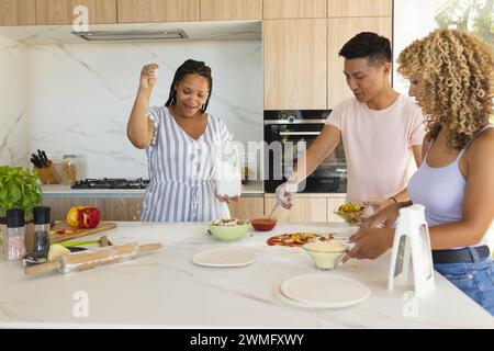 Young Asian man and biracial women cooking together in a modern home kitchen and making pizza Stock Photo
