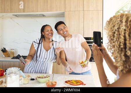 Young Asian man and young biracial woman pose for a photo in a home kitchen, making pizza Stock Photo