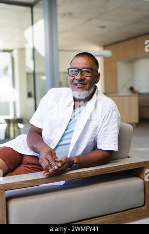 A senior smiling biracial man sits comfortably at home Stock Photo
