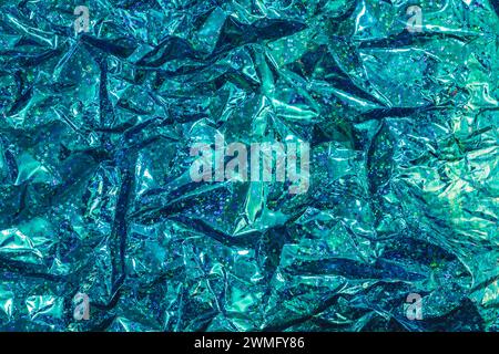 Crinkled blue foil with sparkling details creating an abstract glittering background Stock Photo