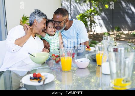 Biracial couple enjoys breakfast outdoors with their granddaughter Stock Photo