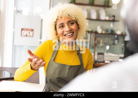 A young biracial woman engages in conversation at a cafe Stock Photo