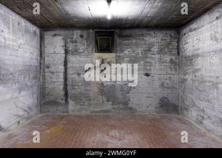 Front view of reinforced concrete wall with a small window for air. Scene illuminated by a white neon lamp. Nobody inside Stock Photo