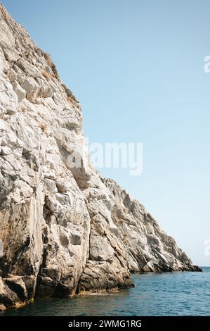 Rugged cliffs in blue seawater along Santorini coastline Stock Photo
