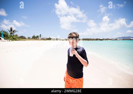 Tween Boy Drinks From Straw Cup on Caribbean Beach Stock Photo