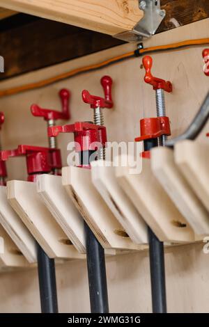 Red woodworking clamps lined up in a workshop. Stock Photo