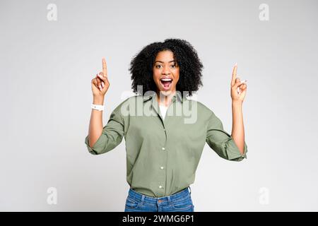 The African-American woman points to herself with a surprised and excited expression, as if she's just received great news. The concept suggests self-recognition or being chosen for something special. Stock Photo