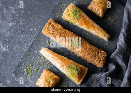 Traditional turkish dessert concept, kadayif, carrrot slice, antep baklava with pistachio on rustic background Stock Photo