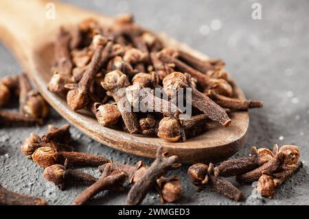 Dry cloves in wooden bowl on rustic table, fresh herb spice concept Stock Photo