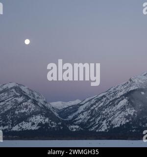 Daybreak with moonset above the Teton Range, purple sky over snow covered mountains, hills, close to Jackson Hole, Wyoming, USA Stock Photo