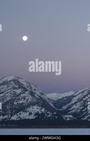 Daybreak with moonset above the Teton Range, purple sky over snow covered mountains, hills, close to Jackson Hole, Wyoming, USA Stock Photo