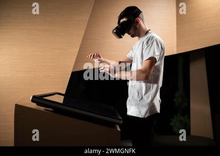 Young man interacting in a digital world, using virtual reality headset with motion tracking tech, making hand gestures in the air. Stock Photo