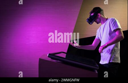 Young man interacting in a digital world, using virtual reality headset with motion tracking tech, making hand gestures in the air. Stock Photo