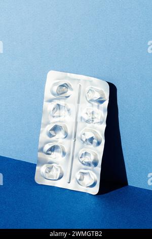 Empty medicine blister pack leaning on blue background. Isolated studio shot. Stock Photo