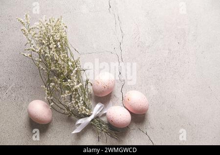 Pink Easter eggs with golden spots  and gypsophila flowers on gray stone background with copy space. Stock Photo