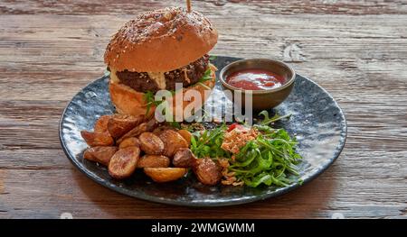 Plate with Beef burger and fried potatoes on textured wooden table Stock Photo