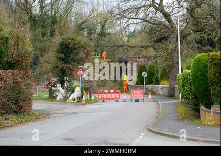 Contractors working on an old railway bridge to clear vegitaion and scrub from the area behind a road closure sign. Stock Photo