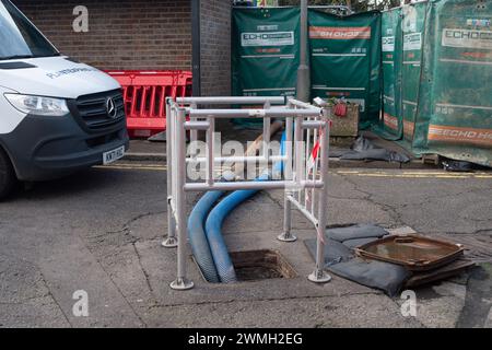 Chalfont St Peter, UK. 26th February, 2024. Part of the village of Chalfont St Peter remains closed to vehicles as Thames Water and their contractors are continuing to pump up groundwater and sewage from manholes in the village of Chalfont St Peter in Buckinghamshire. Thames Water have reportedly been there since 2nd January, 2024. Thames Water have been pumping sewage directly into the River Misbourne, a precious chalk stream. The stream has sewage floating in it including dirty toilet paper. Part of the road also has sewage on it. The ongoing sewage scandal is having a very detrimental impac Stock Photo