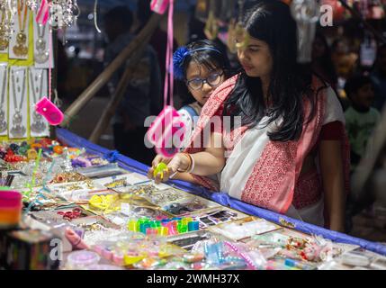 Birbhum, West Bengal, India - February 26th 2024: An woman and a girl buying from a stall in a rural fair at night Stock Photo