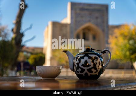 tea in the oriental tradition. porcelain cup and teapot against the background of a beautiful madrasah, architecture in the medieval style of Central Stock Photo