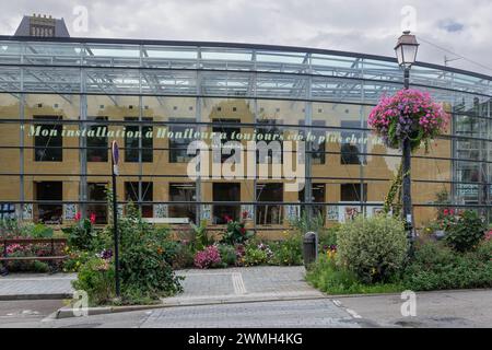 Honfleur, France - Focus on the Media library Maurice Delange, modern glass building complex with a large flower bed in the historic city center. Stock Photo