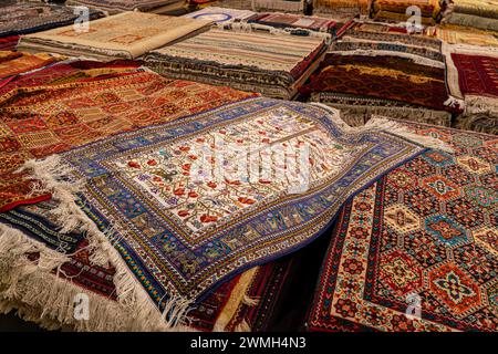 Variety of the gorgeous oriental carpets in traditional carpet store in Middle East. Pile of beautiful handmade carpets on the traditional Middle East Stock Photo