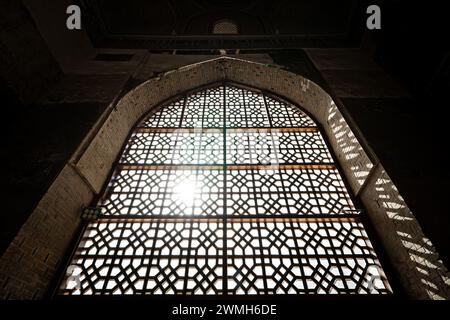 Oriental style window with bar and sun shining through it. the grille on the window. Traditional Islamic style in the architecture and interior of the Stock Photo