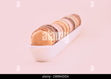Brown and orange french macaroons on a plain pastel colored background Stock Photo