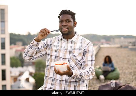 Hungry African American man holding bowl of fresh salad. Stock Photo