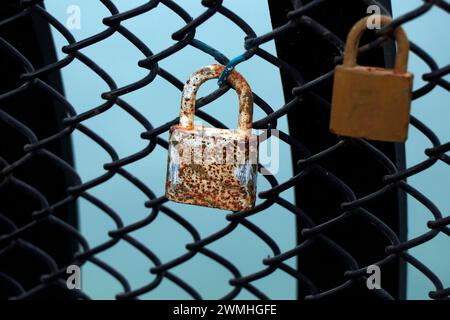 old rusty colorful padlocks locked on a net wall Stock Photo