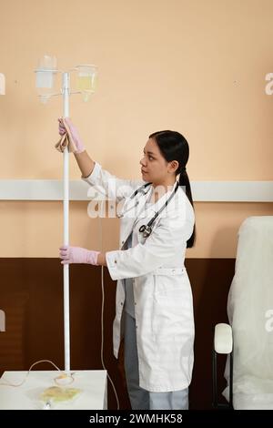 Vertical portrait of young female nurse desinfecting and cleaning equipment in procedure room at clinic Stock Photo