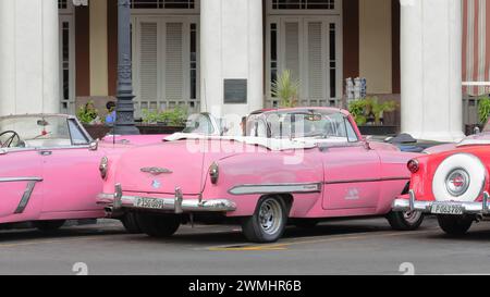 020 Pink and red American classic cars -almendron, yank tank Mercury-Chevrolet-Ford- from 1953- stationed on Paseo del Prado promenade. Havana-Cuba. Stock Photo