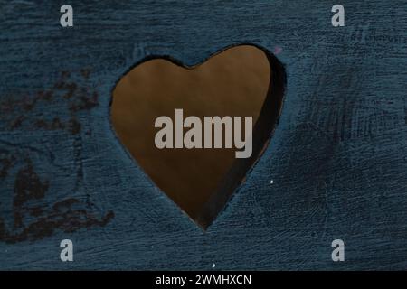 One heart shaped see-through hole in an old blue wood Stock Photo