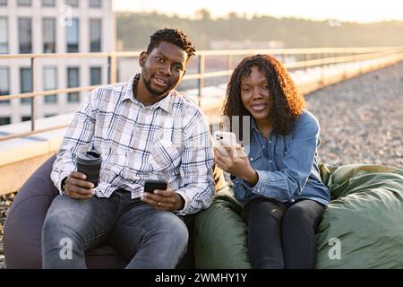 African businesspeople, man and woman sitting on lunch break on beanbags. Stock Photo