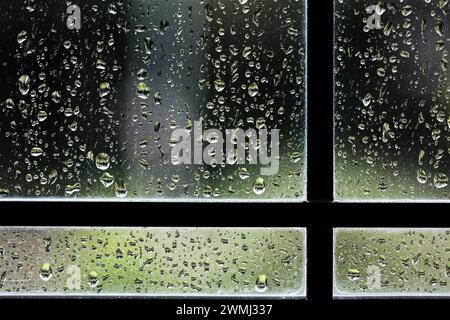 Raindrops on leaded glass window pane close up. The photo of this wet weather background was taken indoors looking into a garden Stock Photo