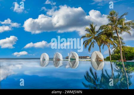 View from the pool reflections beachfront resort with palm trees. Loungers leisure and sun chairs umbrella. Luxury vacation tourism concept. Stock Photo