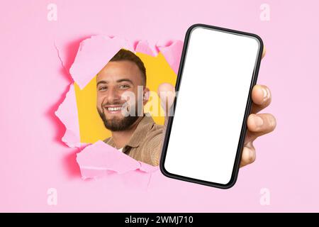 Smiling bearded man in a corduroy shirt peeks through a pink torn paper Stock Photo