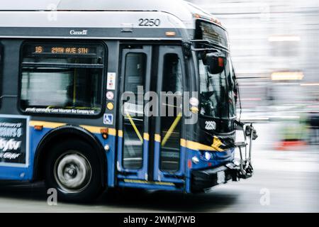 Vancouver, Canada - Feb 21 2024: A bus is crossing Georgia Street, driving down Granville Street. The bus and background appear blurred. Stock Photo