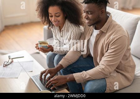 Black couple engaged with paperwork and laptop in living room Stock Photo