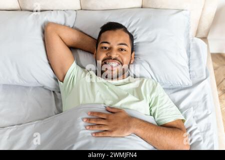 Positive young african american man laying in bed Stock Photo