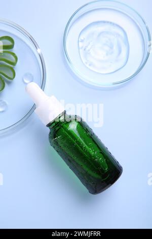 Cut aloe vera, bottle and cosmetic gel on light blue background, flat lay Stock Photo